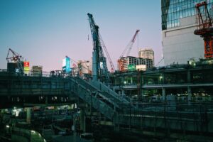 A bustling construction scene in Tokyo, Japan featuring cranes and buildings at dusk.