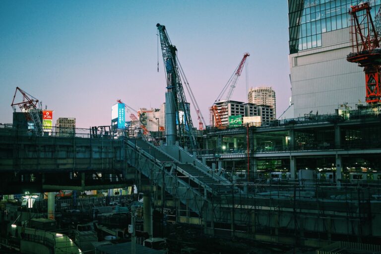 A bustling construction scene in Tokyo, Japan featuring cranes and buildings at dusk.