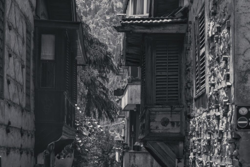 Black-and-white photo of an alley with historic architecture and wooden shutters.