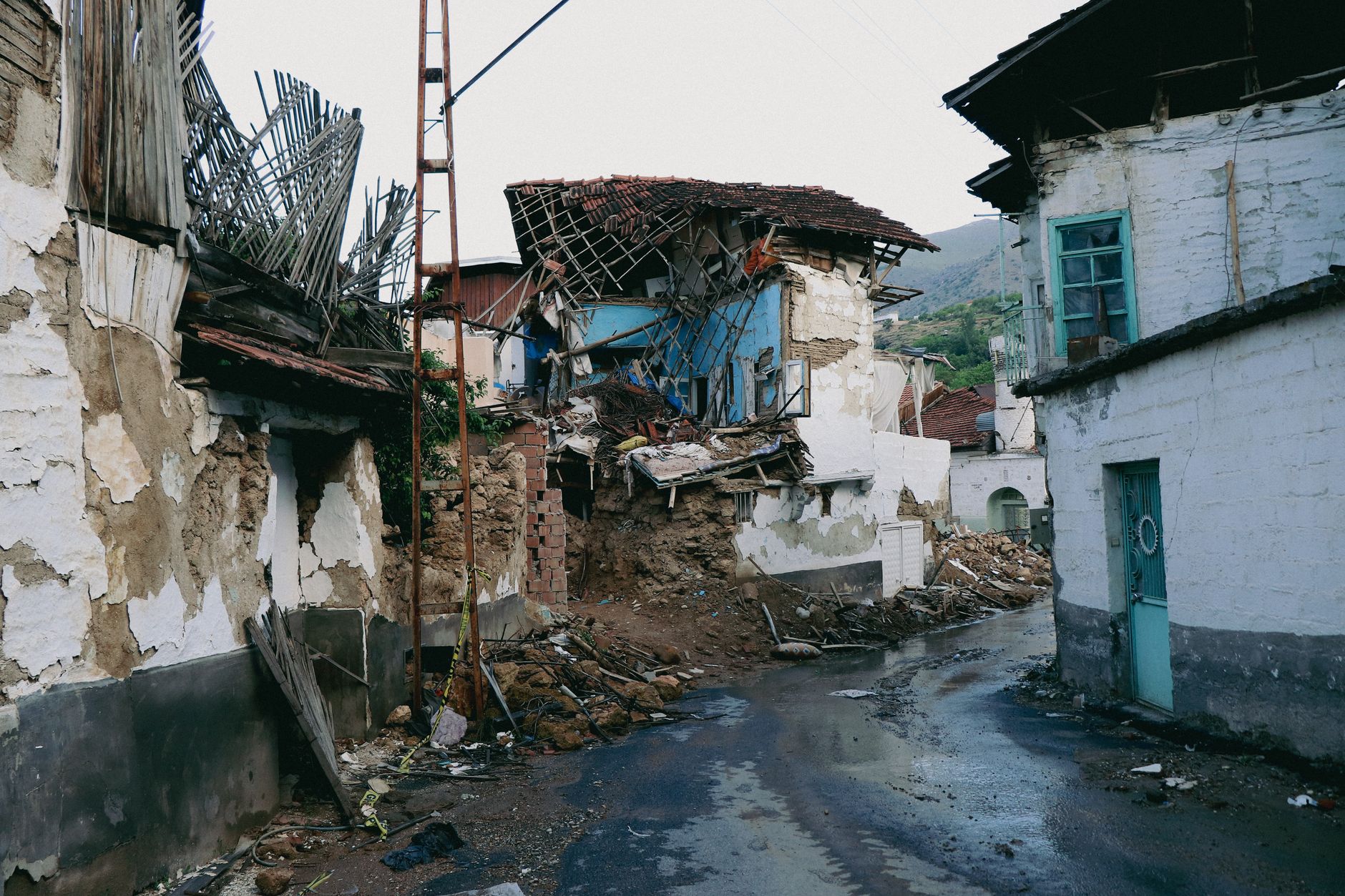 A devastated urban street in Malatya, Turkey after an earthquake, showcasing collapsed traditional houses.