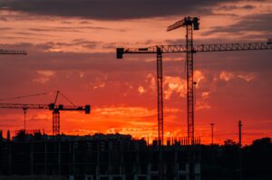 Silhouette of construction cranes against a vibrant sunset in Kaliningrad, Russia.
