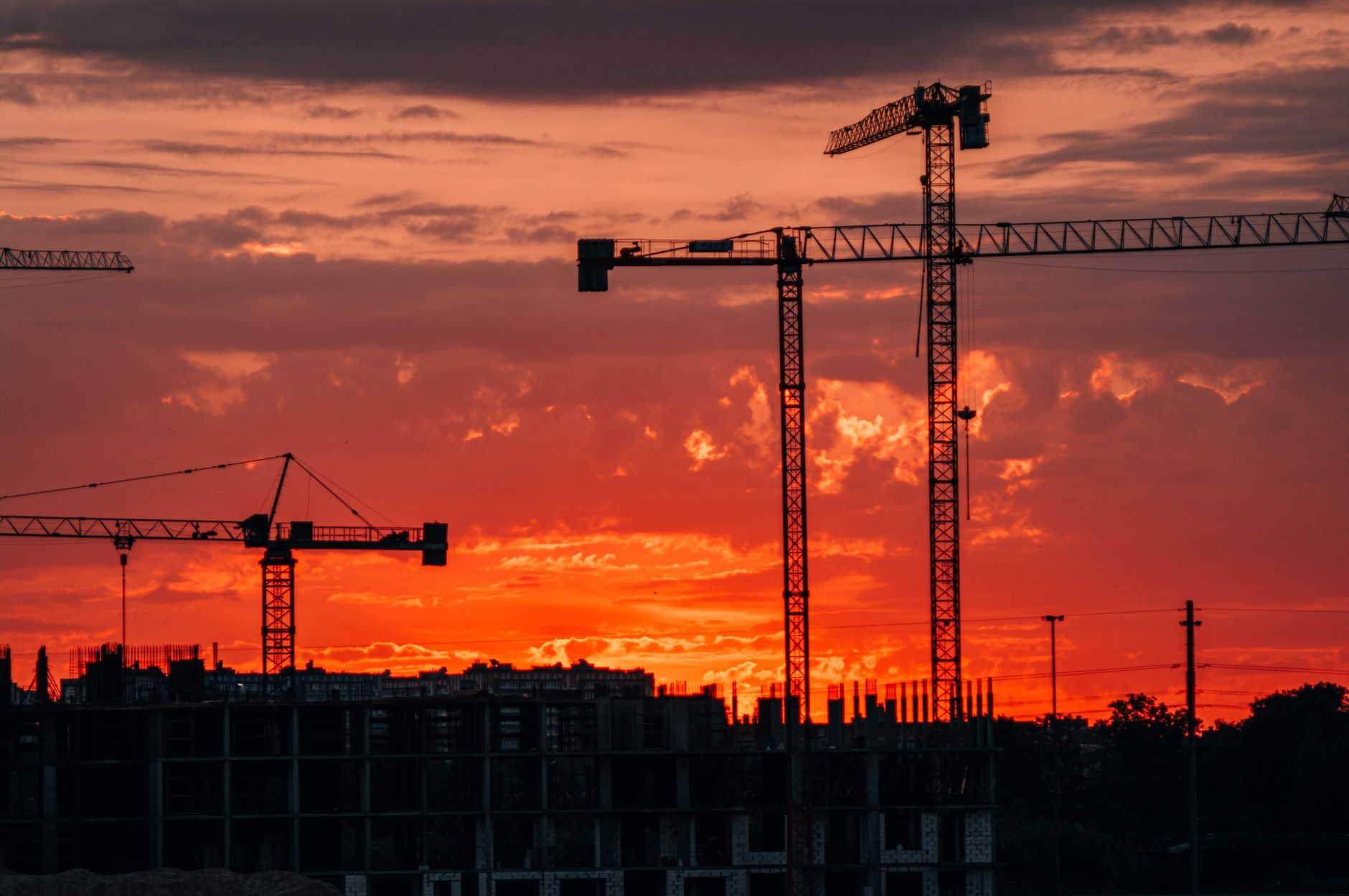 Silhouette of construction cranes against a vibrant sunset in Kaliningrad, Russia.