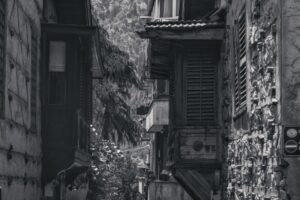 Black-and-white photo of an alley with historic architecture and wooden shutters.