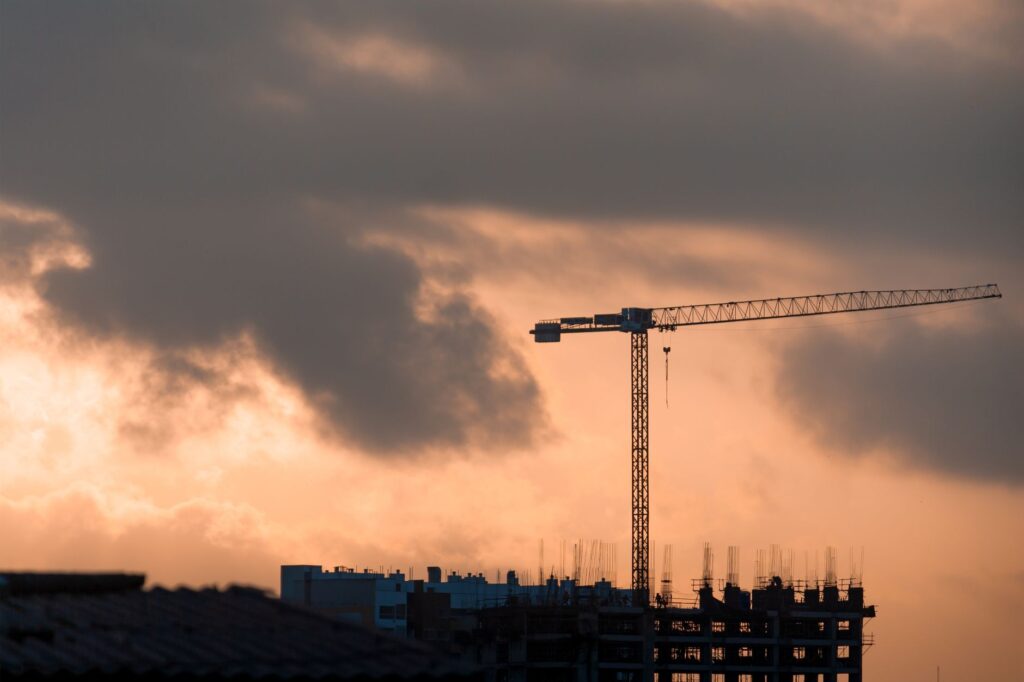 Silhouette of a construction crane against a vibrant sunset in Lima, Perú.