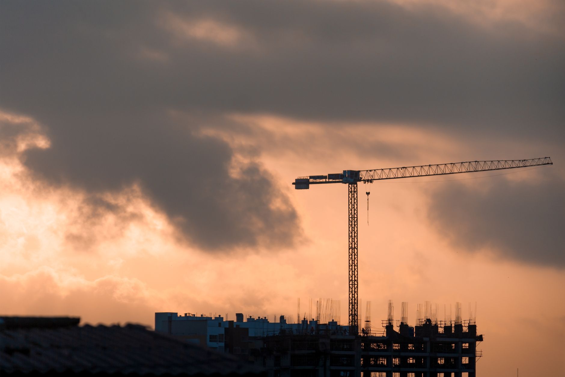 Silhouette of a construction crane against a vibrant sunset in Lima, Perú.