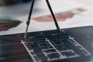 A compass on architectural blueprints, showcasing planning and measurement details.