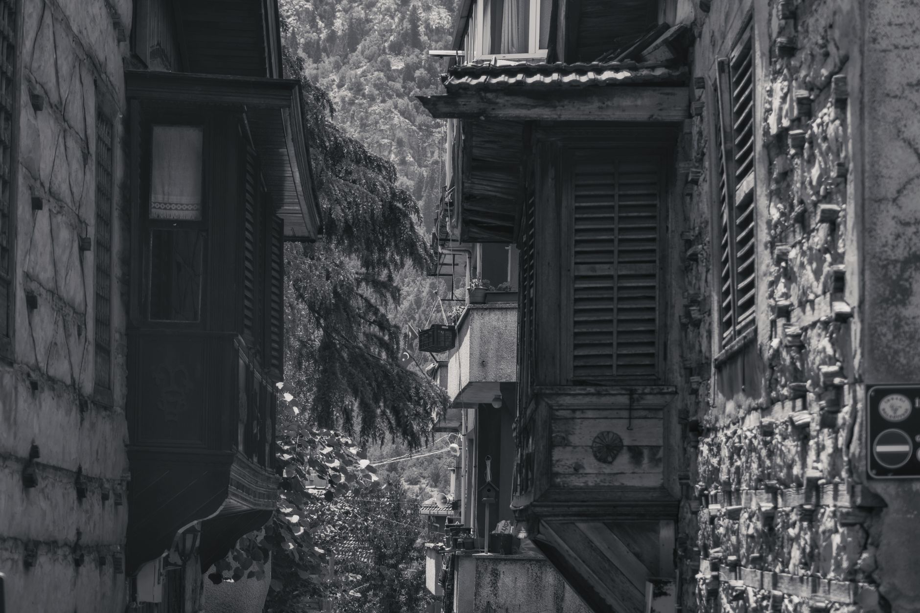 Black-and-white photo of an alley with historic architecture and wooden shutters.
