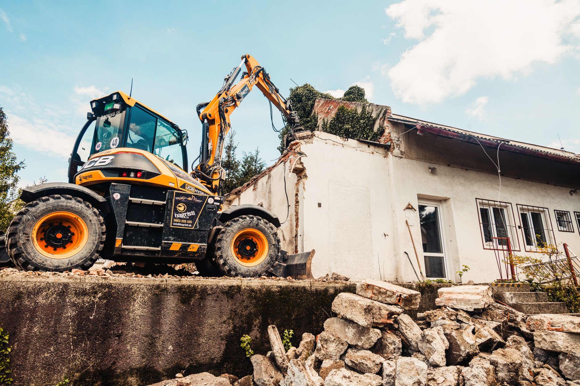 Powerful excavator tearing down an old house during a demolition project outdoors.