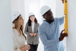 Group of diverse contractors collaborating on a construction project indoors, using a level bar.