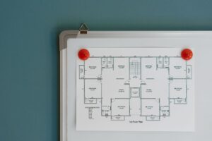 Architecture blueprint of floor in modern office on paper hanging on whiteboard with red magnets on colorful wall in room