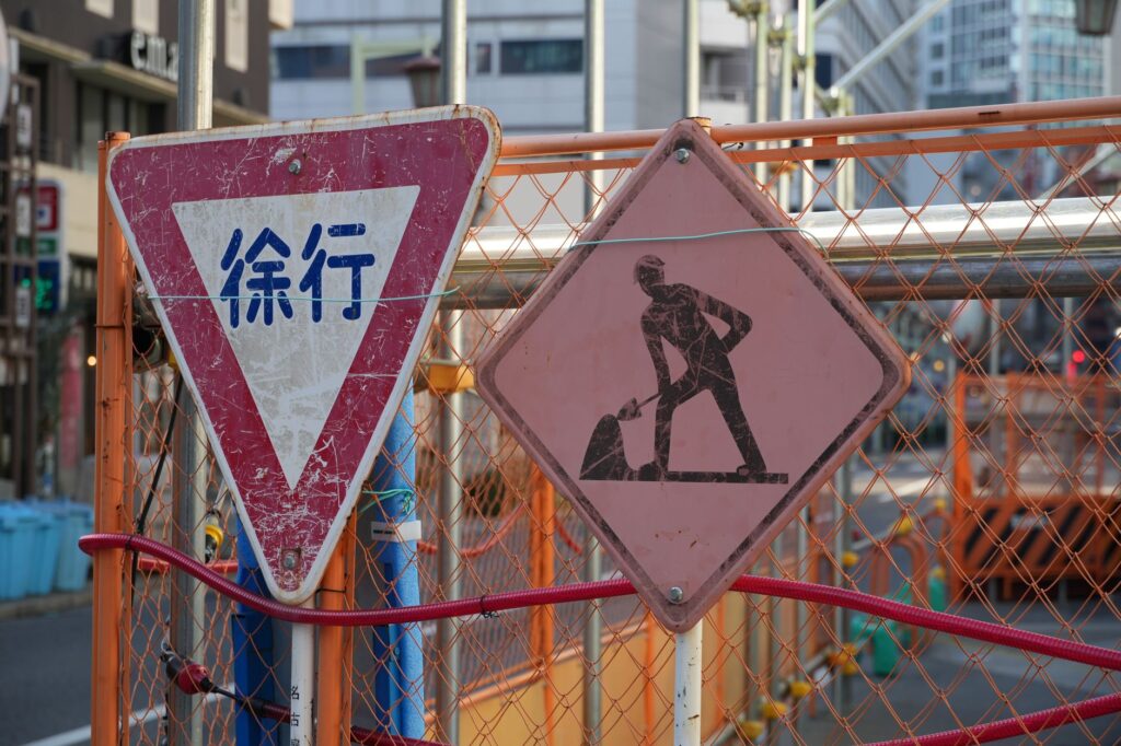 A construction site in a city with Japanese warning and roadwork signs.