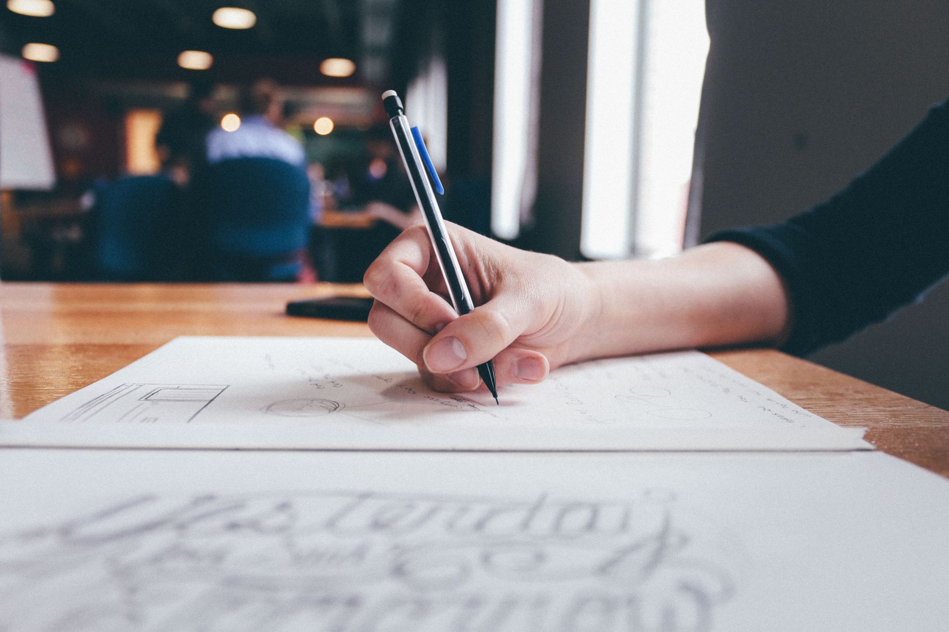 A person focuses on writing or sketching in a creative workspace setting.
