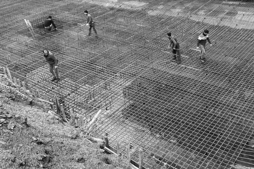 Black and white image of workers on a steel grid at a construction site.