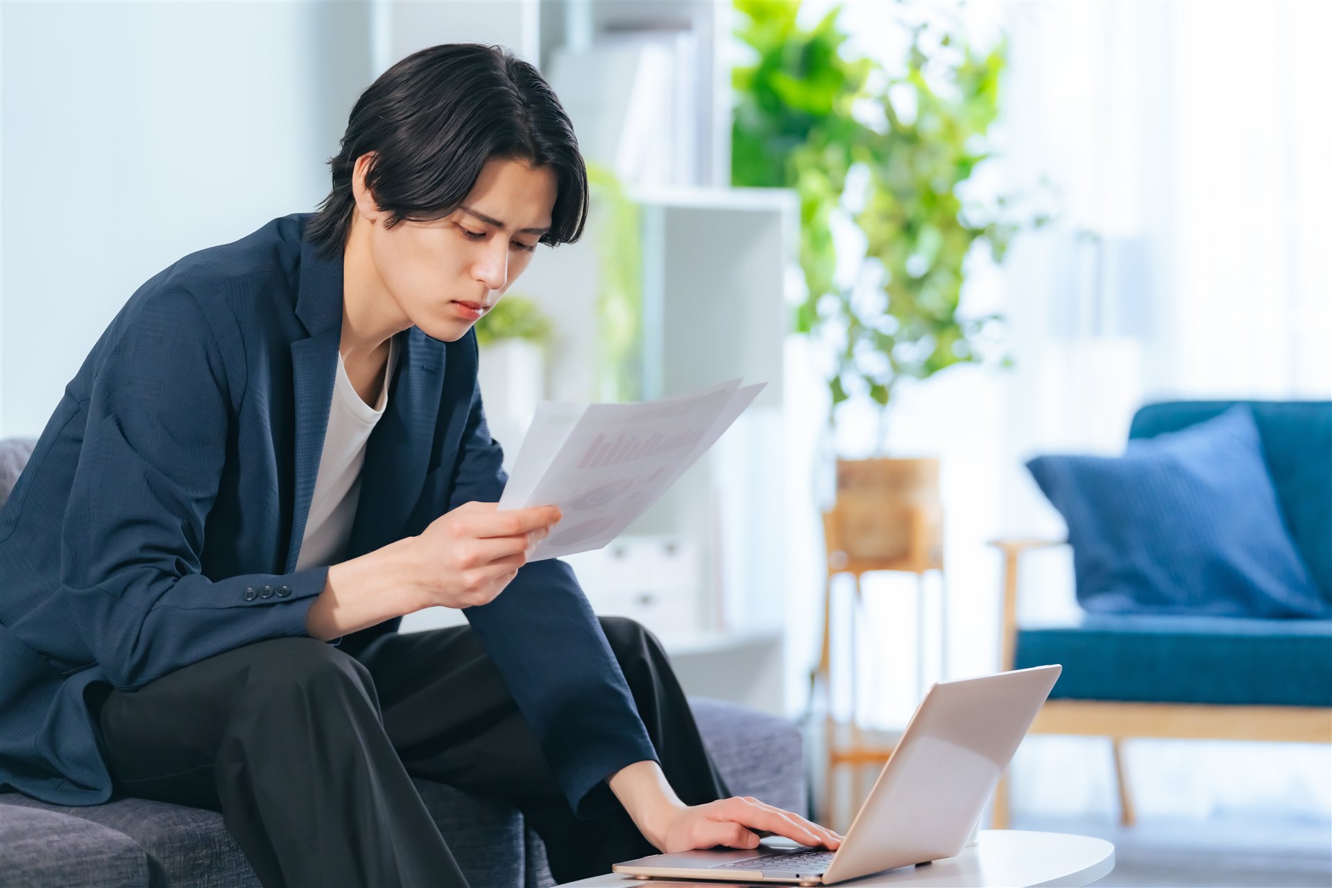 書類を見ながらノートパソコンで手続きをする男性