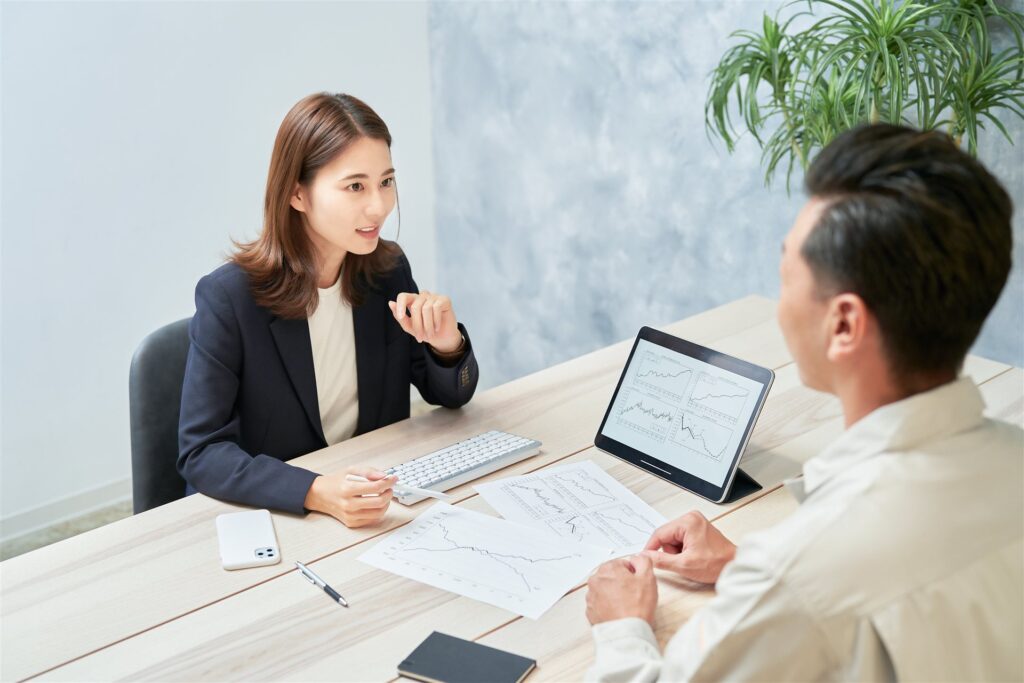 タブレットのグラフを前に向かい合って話す2人