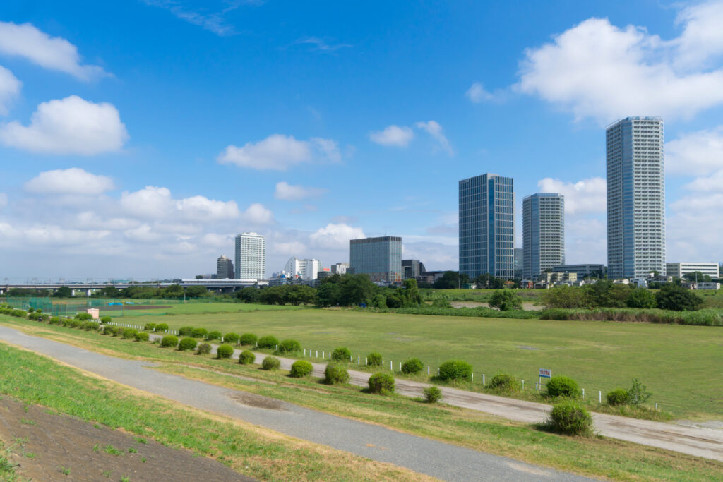 河川敷の緑地と奥に並ぶ中高層の建物