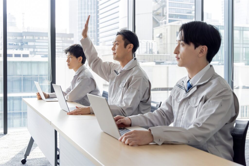 ノートパソコンを前に研修を受ける作業着の3人