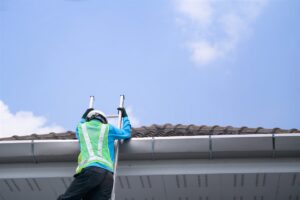 はしごで瓦屋根の軒先へ上る作業員の後ろ姿