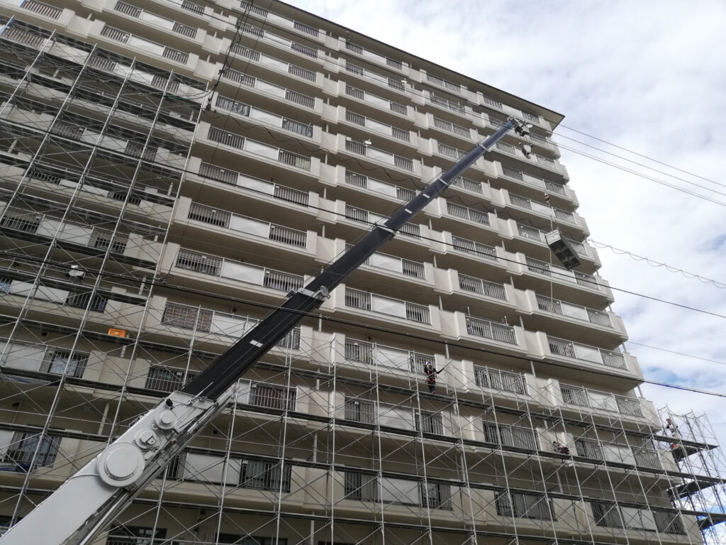足場を組んだ集合住宅とクレーンの現場
