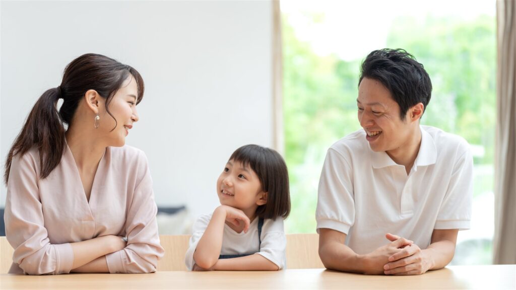 リビングのテーブルで話し合う父と母と子