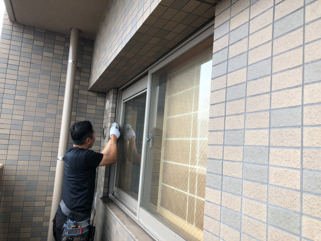 集合住宅の窓まわりを直す作業員の後ろ姿