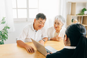 ノートパソコンで高齢の夫婦に説明する担当者