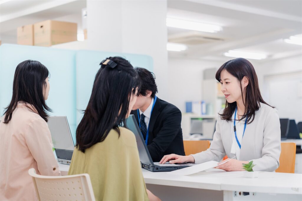 事務所の窓口で来訪者に説明するスタッフ