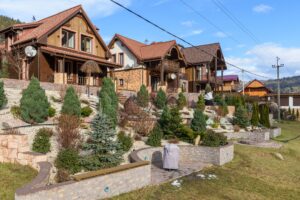 Rustic houses with sloped roofs and landscaped gardens under clear blue skies. Ideal for real estate visuals.