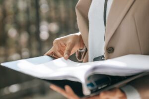 ジャケット姿の女性が黒いファイルの書類を読む