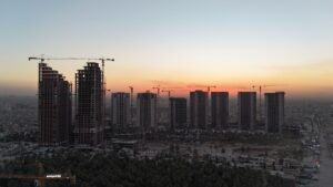 夕焼けの空に並ぶ建設中の高層ビルとクレーン