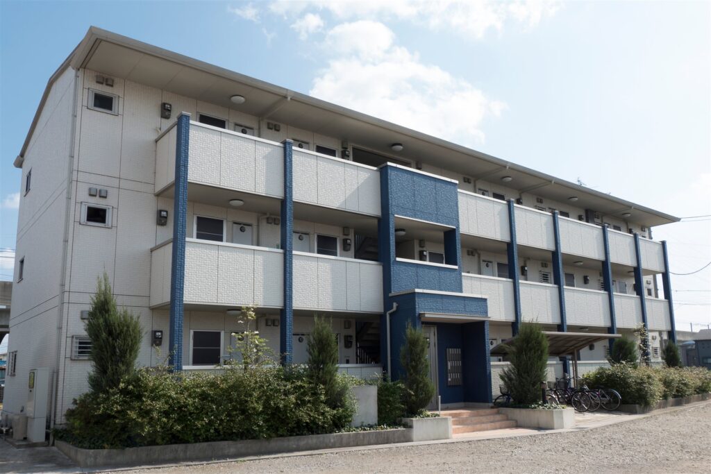 青空の下の白い外壁の3階建て集合住宅
