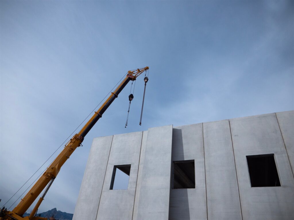 クレーンとコンクリートの壁の部材で組み立てる建物