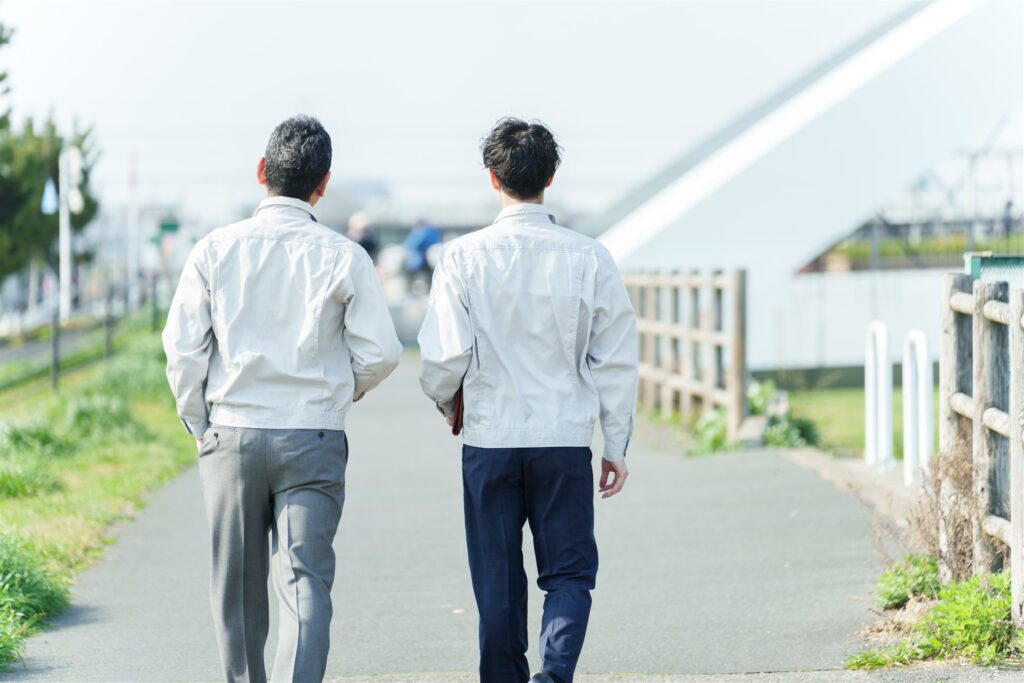 作業着で並んで歩く二人の後ろ姿