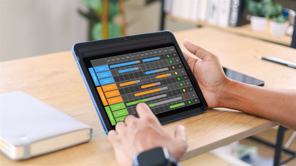 タブレットの色分けの工程表を指で操作する手元