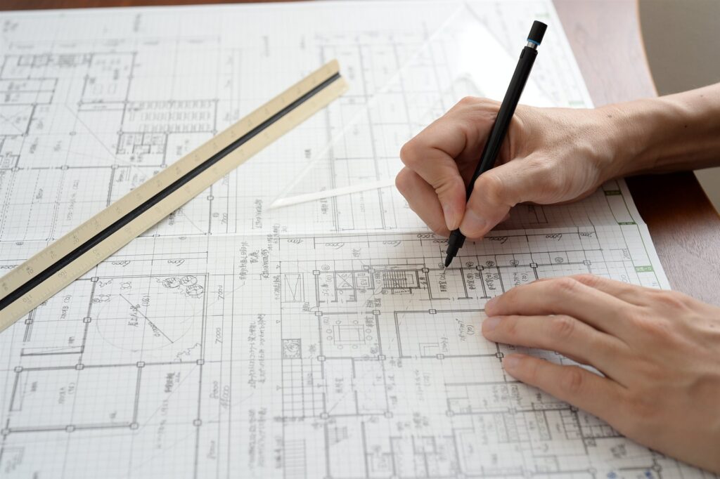住宅の図面に鉛筆で書き込む手元