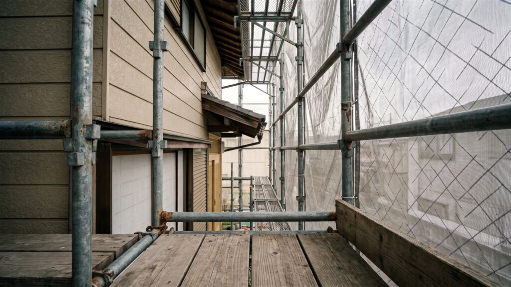 足場の通路から見た住宅の外壁とメッシュシート