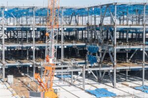 クレーンが立つ鉄骨造の建物の建方の現場