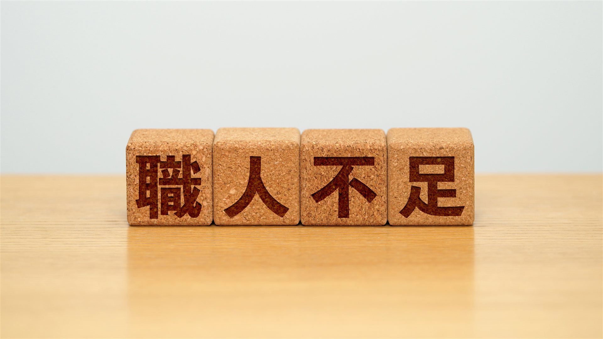 職人不足と彫られた4つのコルクの積み木