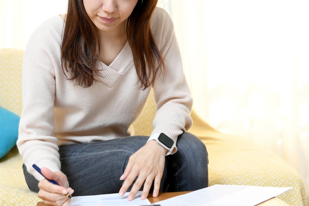 リビングで書類に記入する女性