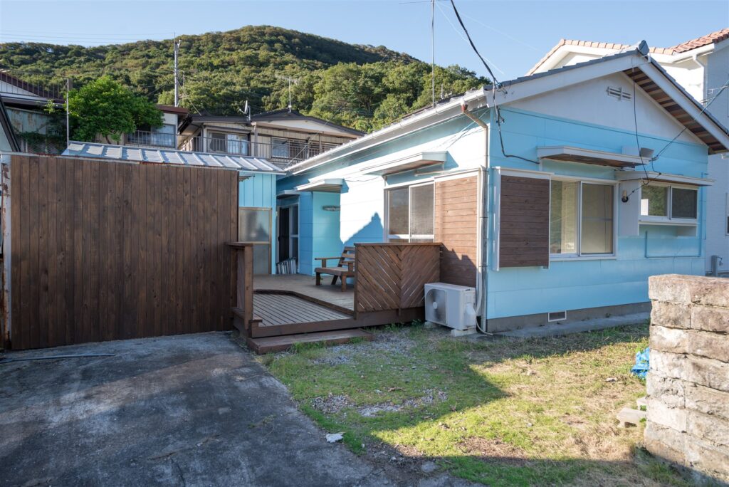 外壁を水色に塗り替えた平屋の住宅とウッドデッキ