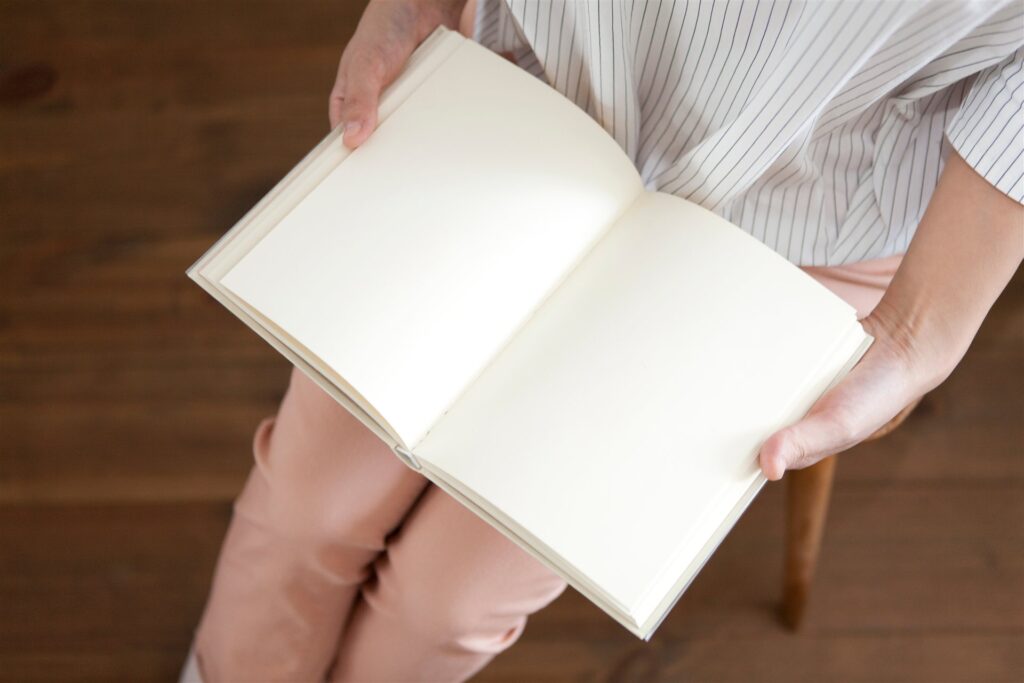 白い頁の本を膝の上で開く手元