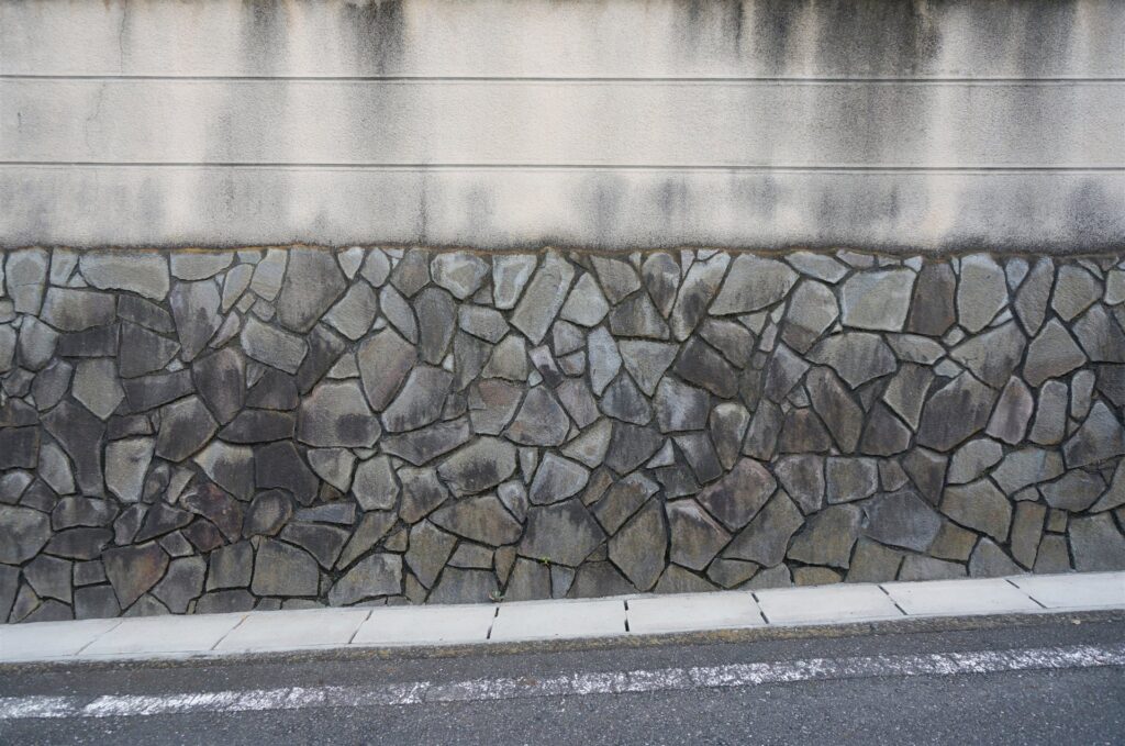 道沿いの石積みとコンクリートの塀