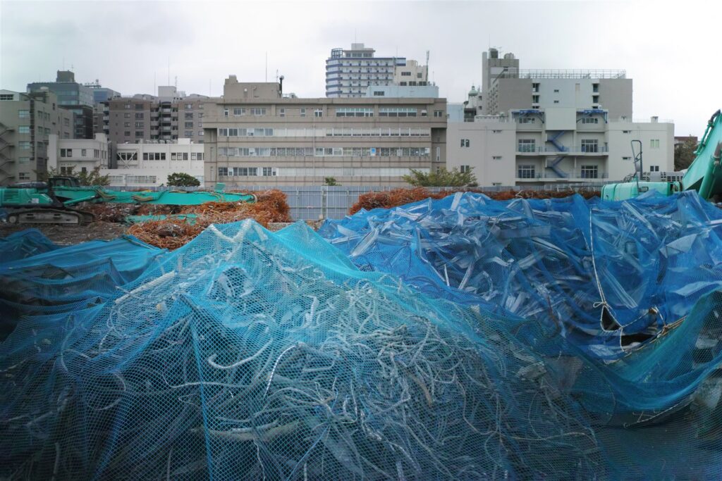 ネットをかけた解体現場の鉄くずの山