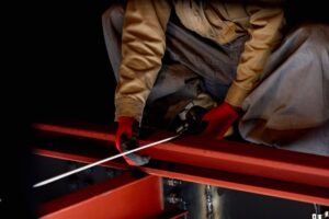 赤い鉄骨の梁の上で作業する職人の手元