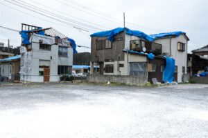 屋根と外壁にブルーシートを掛けた2階建ての住宅