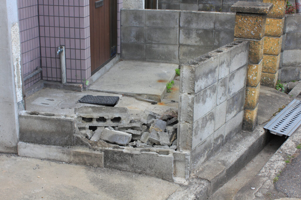 住宅の玄関先で一部が崩れたブロック塀