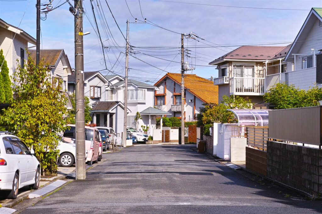 電柱と戸建て住宅が並ぶ住宅街の道