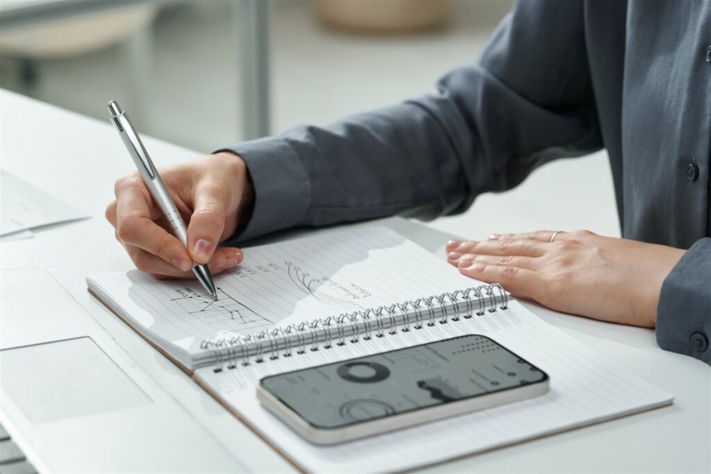 ノートに書き込む手元とスマートフォン