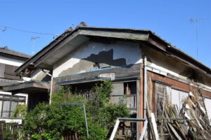 壁の塗りがはがれ板が崩れかけた古い木造の空き家