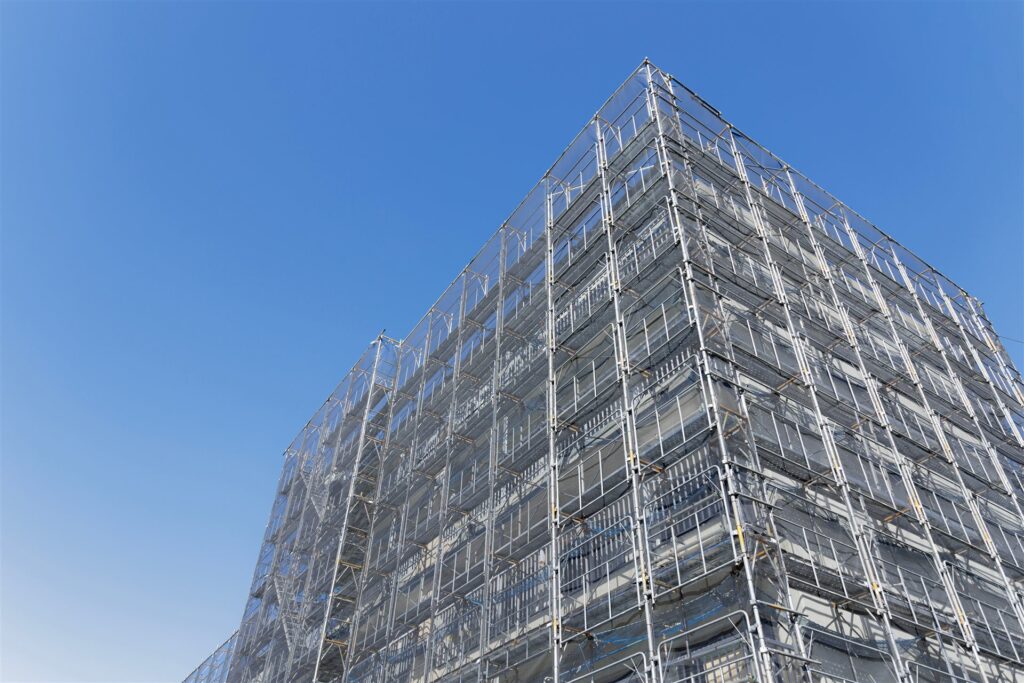 青空の下で足場に囲まれた中層の建物